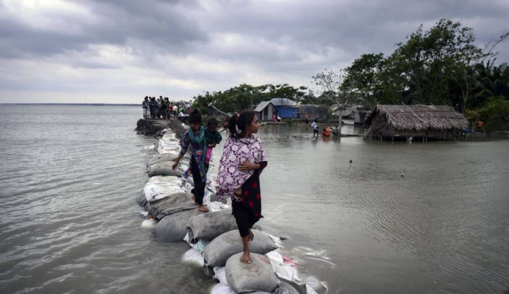 Children walk over the top of a sandbag embankment that was breached by high waters in Khulna on May 4, 2019, after Cyclone Fani reached Bangladesh. Photo: AFP